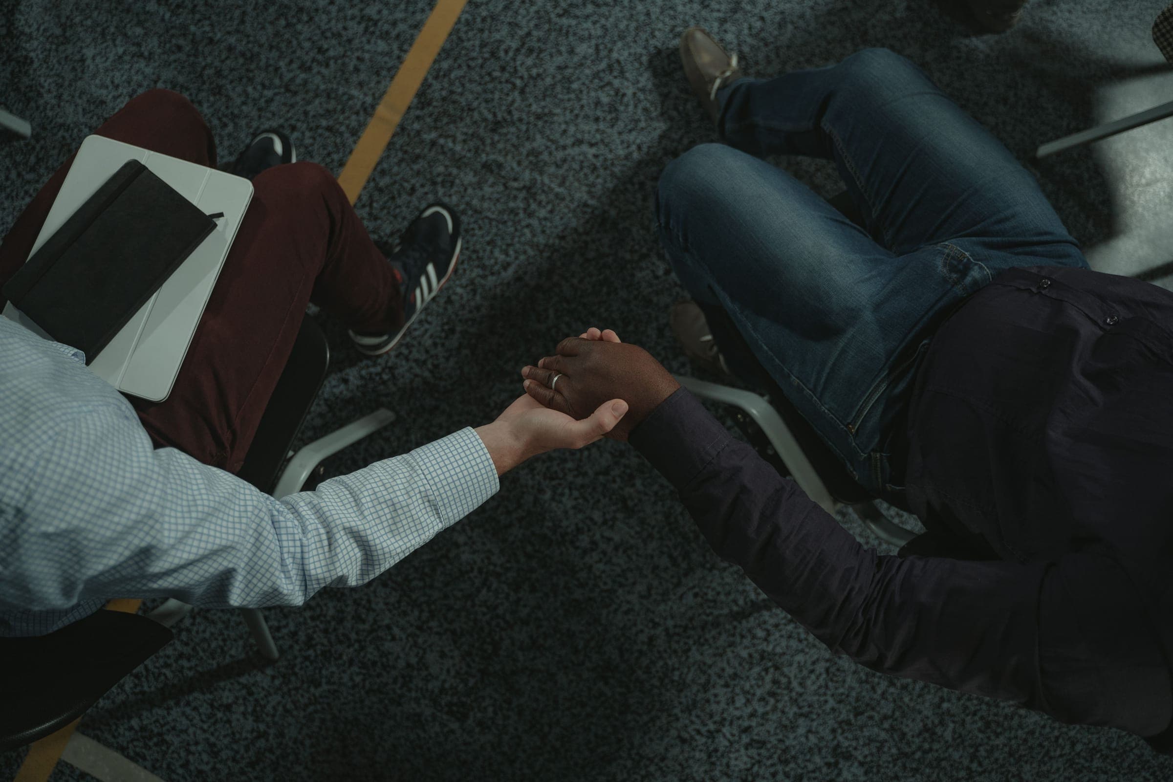 A counsellor reaching for a client's hand, a tablet on her knee