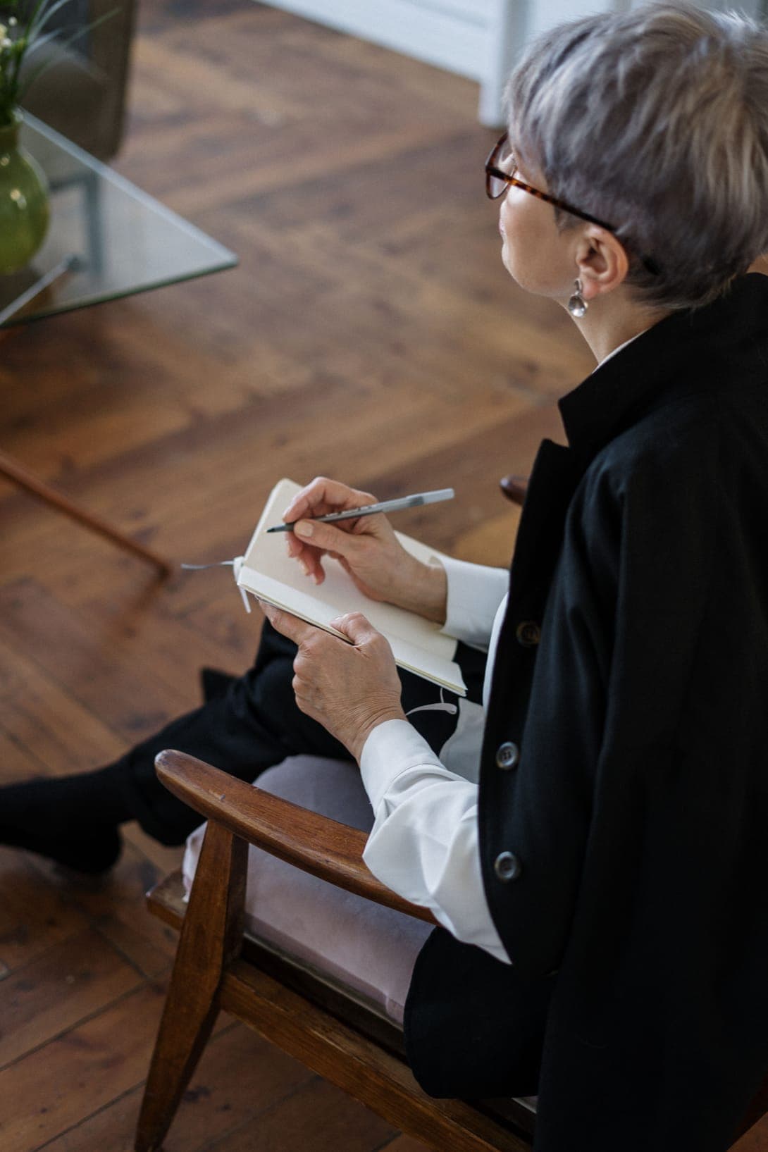 A grey-haired therapist taking notes in a leather chair