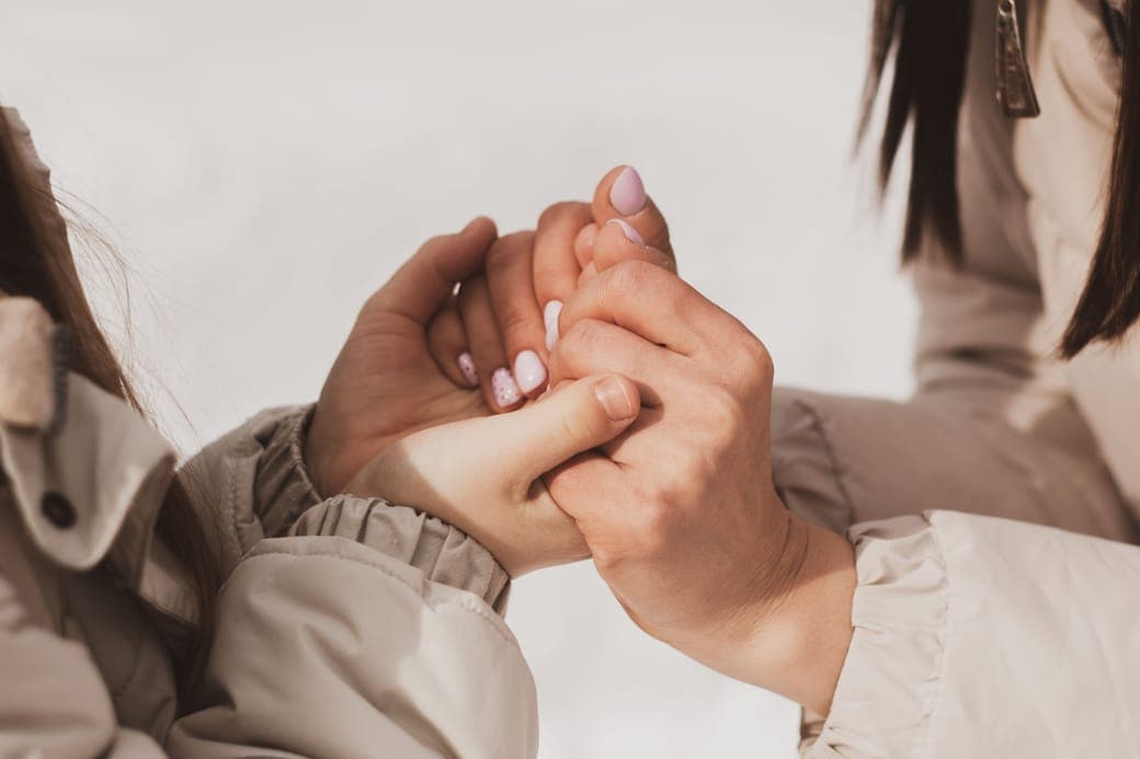 One person holding another's hands in comfort