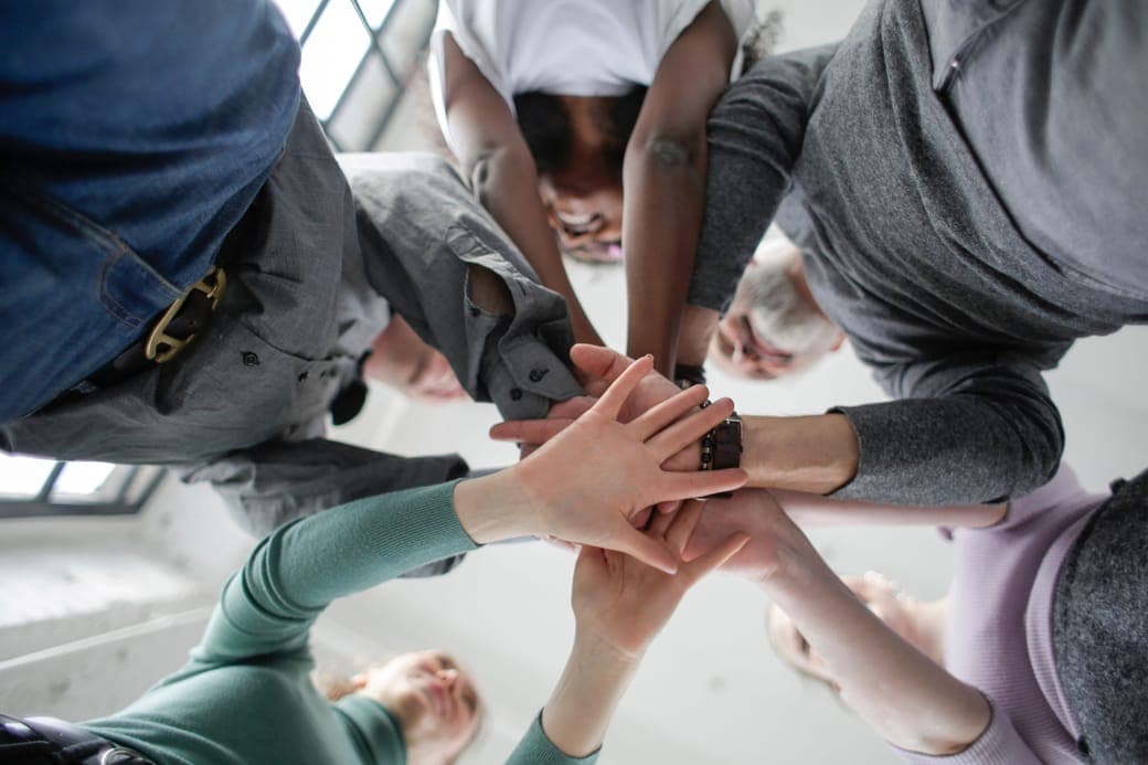 A group stacking their hands in a circle, seen from below