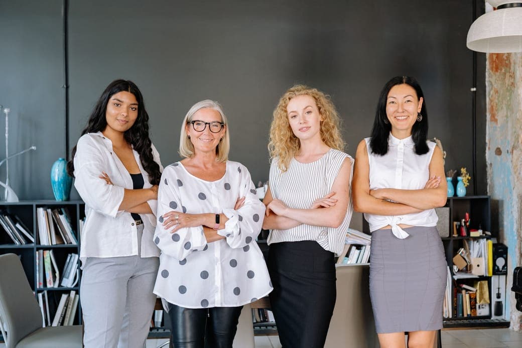 Four women standing with their arms crossed in a studio