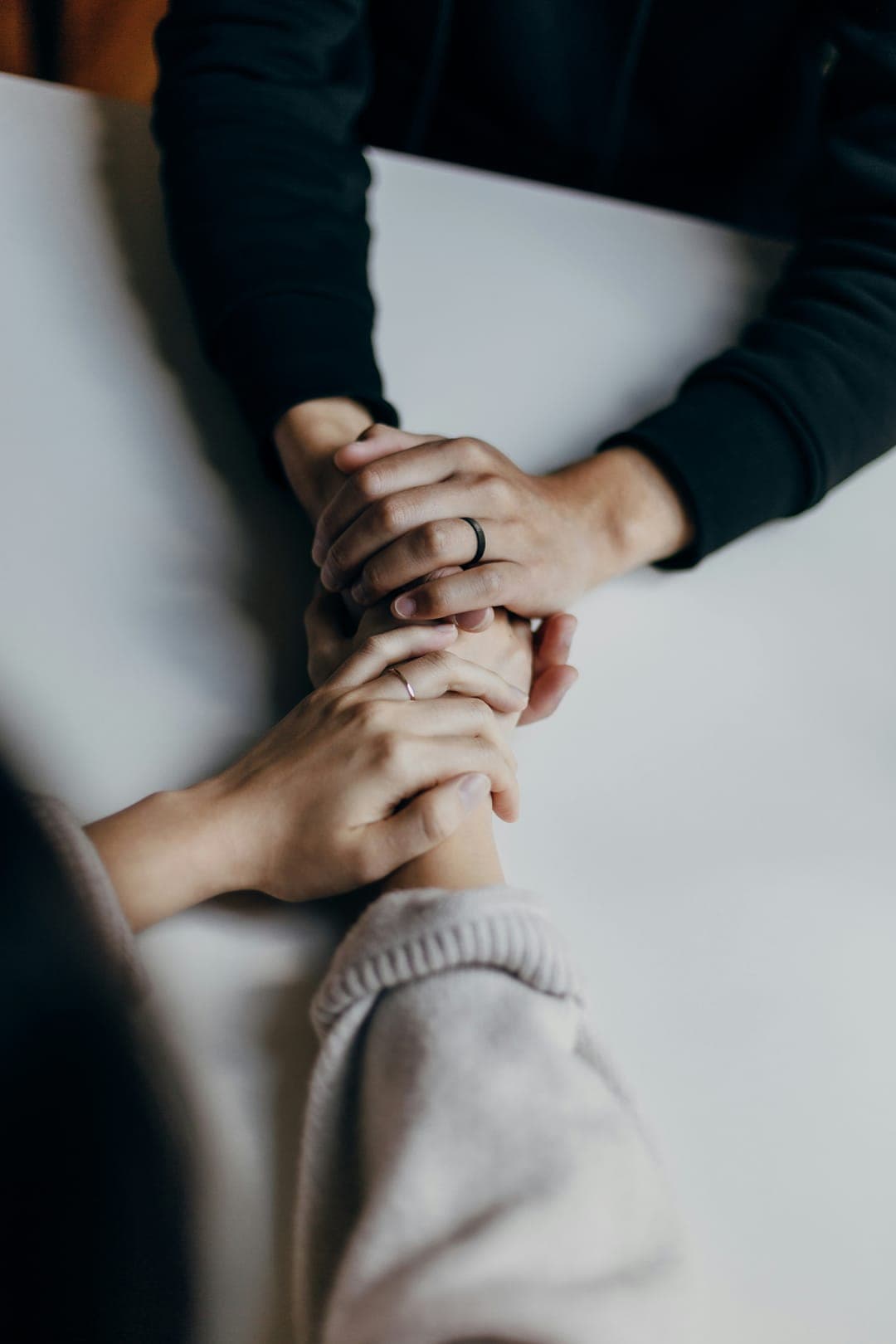 Two people holding hands across a white table