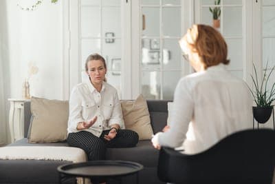 A woman listening on a sofa while a coach talks