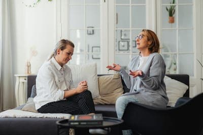 Two women in conversation on a dark sofa