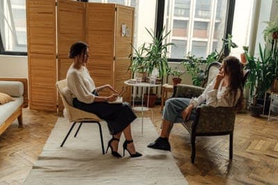 A counsellor and a client talking in a room with folding screens