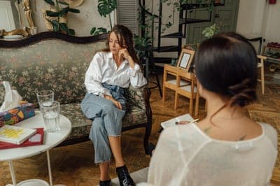 A woman on a vintage sofa talking with a counsellor