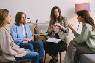 A small group sitting in a circle under a pink lamp