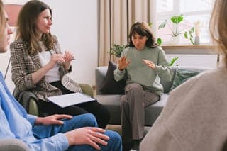 A woman with a notebook leading a small group on a sofa
